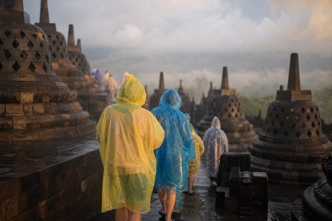 Climbing Borobudur's wet steps in rain ponchos